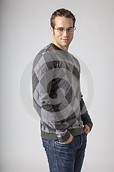 Man wearing argyle sweater, jeans and eyeglasses. Young men`s casual fall fashions clothing apparel styles. photo