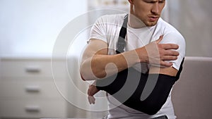 Man wearing arm sling feeling pain in shoulder, result of trauma, orthopedics