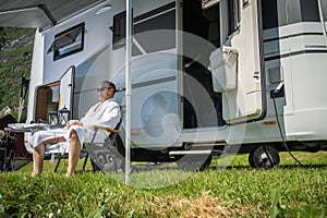 Man Wearing Bathrobe Enjoying Early Morning in a RV Park in Front of His Camper Van