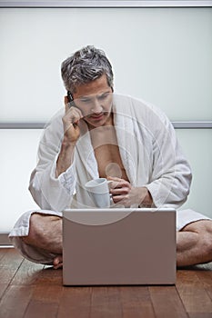 Man wearing bathrobe and talking on a mobile phone