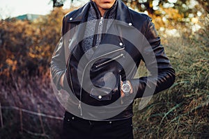 Man wearing black leather jacket and watch posing outdoors