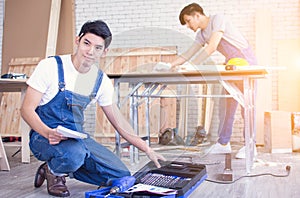 Man wearing blue apron and openning tools box for making wooden furniture