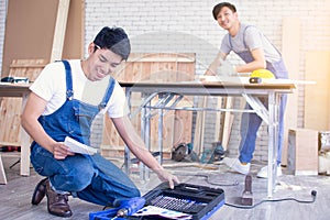 Man wearing blue apron and openning tools box for making wooden furniture