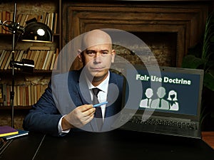 Man wearing blue business suit and showing laptop with written text Fair Use Doctrine . Blurred background. Horizontal mockup