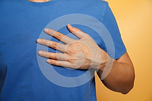 man wearing a blue shirt has chest pain caused by heart disease, heart attack, leaky heart disease, coronary artery disease during