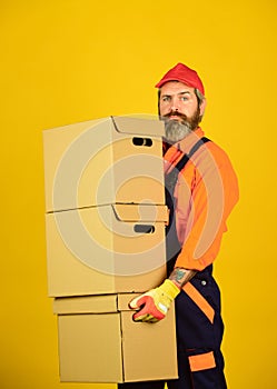 Man wearing boilersuit packing boxes. move to new apartment. bearded loader in uniform. Cardboard boxes - moving to a