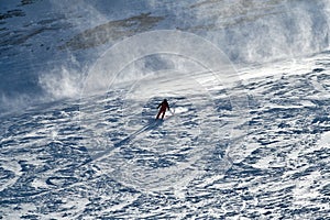 Man wearing bright red suit skiing on snowy backcountry bowl area. Extreme winter sports.