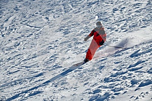 Man wearing bright red suit skiing on snowy backcountry bowl area. Extreme winter sports.