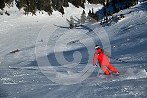 Man wearing bright red suit skiing on snowy backcountry bowl area. Extreme winter sports.