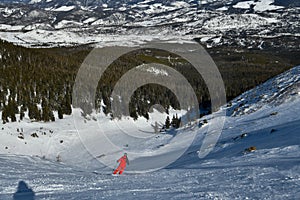 Man wearing bright red suit skiing on snowy backcountry bowl area. Extreme winter sports.