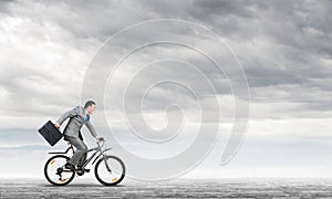 Man wearing business suit riding bicycle outdoor.