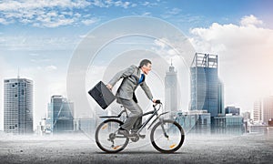 Man wearing business suit riding bicycle outdoor.