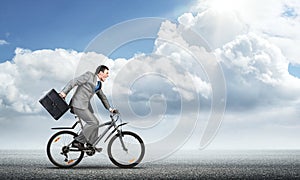 Man wearing business suit riding bicycle outdoor.