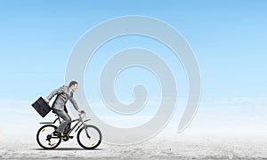 Man wearing business suit riding bicycle outdoor.