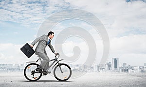 Man wearing business suit riding bicycle outdoor.