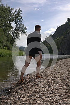 Man wearing businness suit with no pants walking down river