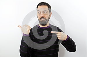 Man wearing casual clothes surprised and doubtful pointing with two hands and fingers to the side