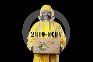 Man wearing chemical protective suit with cardboard box on background. Coronavirus outbreak