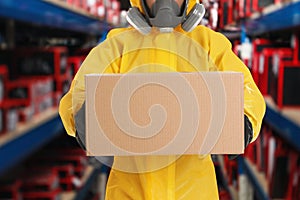 Man wearing chemical protective suit with cardboard box in store. Wholesale market