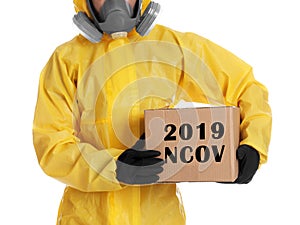 Man wearing chemical protective suit with cardboard box on white background, closeup. Coronavirus outbreak