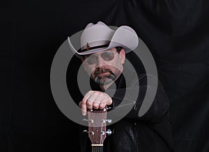 Man wearing cowboy felt hat and shades with guitar
