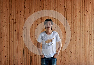 Man wearing Cyprus flag color shirt and standing with two hands in pant pockets on the wooden wall background