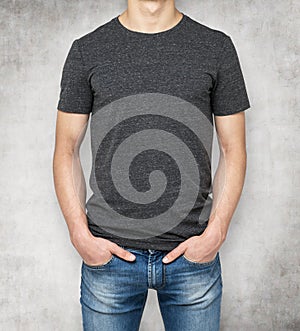 Man wearing dark grey t-shirt, concrete background.