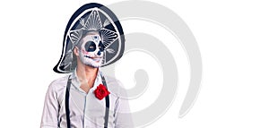 Man wearing day of the dead costume over background looking away to side with smile on face, natural expression