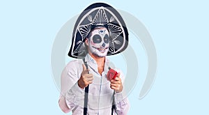 Man wearing day of the dead costume over background pointing fingers to camera with happy and funny face