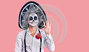Man wearing day of the dead costume over background showing and pointing up with fingers number four while smiling confident and