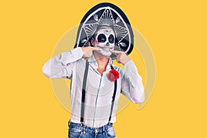 Man wearing day of the dead costume over background smiling cheerful showing and pointing with fingers teeth and mouth