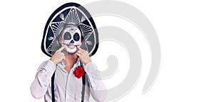 Man wearing day of the dead costume over background smiling with open mouth, fingers pointing and forcing cheerful smile