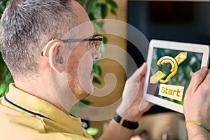 Man wearing deaf aid with tablet