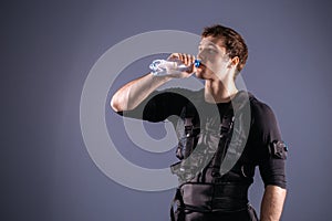 Man wearing electro stimulation suit drink water after training