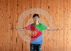 Man wearing Eritrea flag color shirt and standing with arms wide open on the wooden wall background