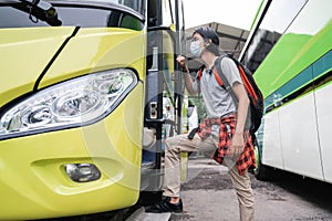 A man wearing face masks getting on the bus.