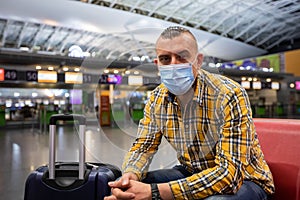 Man wearing face medical mask and waiting for flight at airport