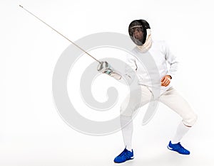 Man wearing fencing suit practicing with sword against gray