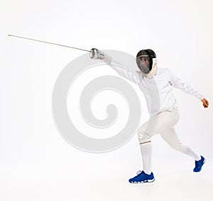 Man wearing fencing suit practicing with sword against gray