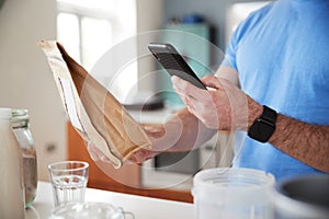 Man Wearing Fitness Clothing Scanning QR Code On Food Packaging To Find Nutritional Information