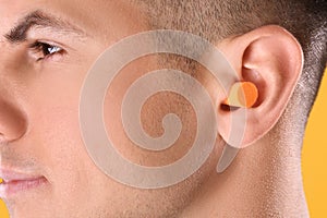 Man wearing foam ear plug, closeup view