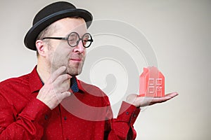 Man wearing funny eyeglasses holding house