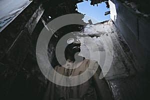 A man wearing a gas mask inside a ruined building in the dark