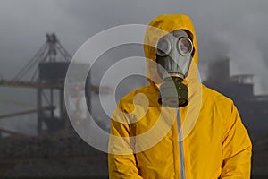 Man wearing gas mask standing infront of factory.