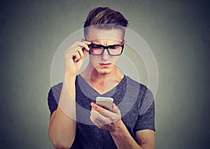 Man wearing glasses having trouble seeing cell phone has vision problems.