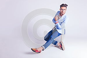 Man wearing glasses posing seated hith hands and legs crossed