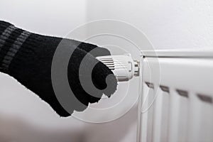 Man wearing gloves adjusting the radiator heat controller knob