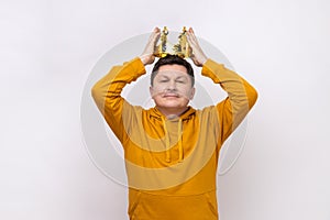 Man wearing golden crown, imagining promotion at work, looking with arrogance, privileged status.