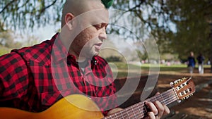 A man wearing a green mohawk singing and playing guitar at park