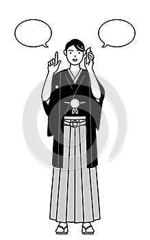 Man wearing Hakama with crest pointing while on the phone